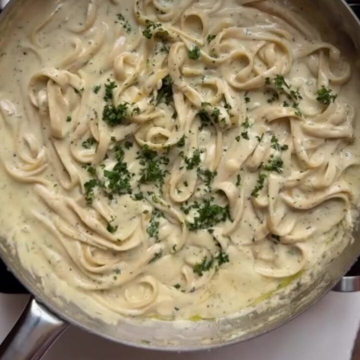 Fettuccine twirled on a fork, coated in a glossy garlic parmesan sauce