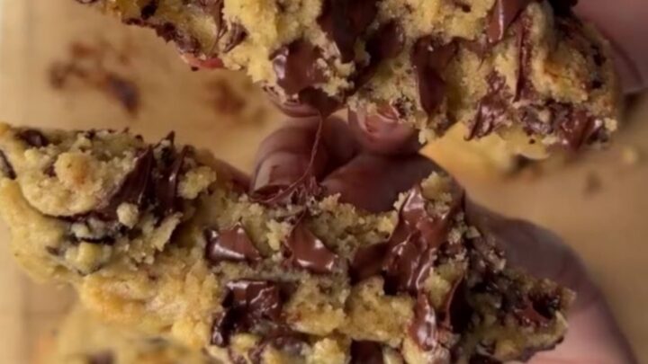 Giant chocolate chip cookie broken open with gooey molten chocolate center