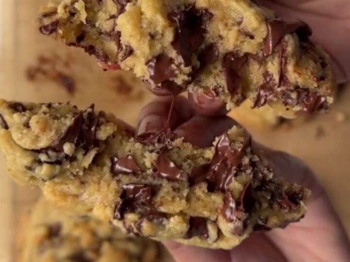 Giant chocolate chip cookie broken open with gooey molten chocolate center