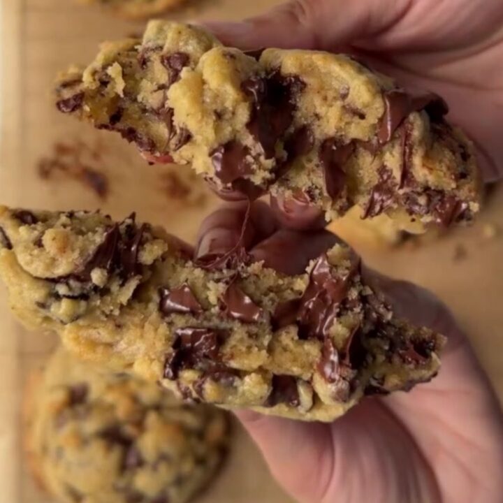 Giant chocolate chip cookie broken open with gooey molten chocolate center