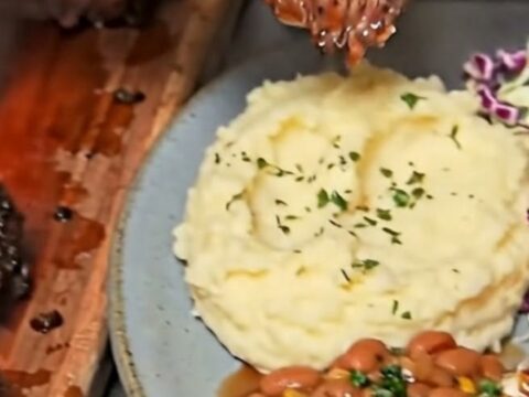 A close-up of a juicy, perfectly smoked beef brisket slice resting on a plate with creamy mashed potatoes.