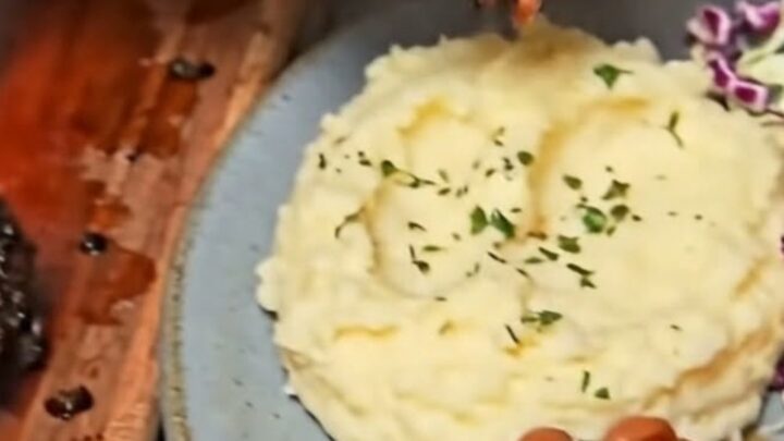 A close-up of a juicy, perfectly smoked beef brisket slice resting on a plate with creamy mashed potatoes.