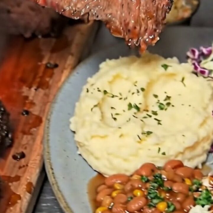 A close-up of a juicy, perfectly smoked beef brisket slice resting on a plate with creamy mashed potatoes.