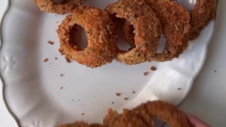 Crispy golden onion rings piled high with a bowl of garlic herb aioli