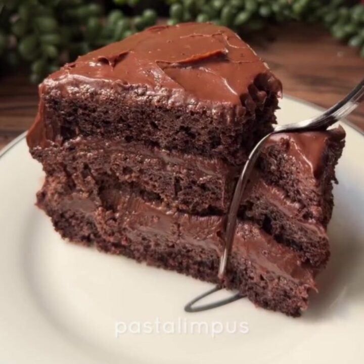 A slice of no-bake chocolate mousse cake with a thick cocoa dusting on top, showing the creamy interior and biscuit base.