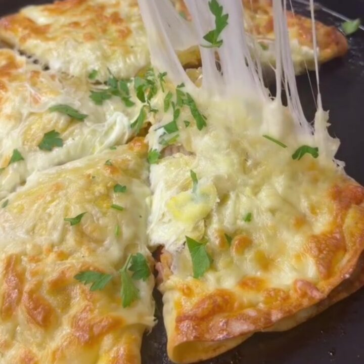 A golden-brown crispy chicken and cheese wrap pie cut into wedges, with melted cheese pulling from the slice.
