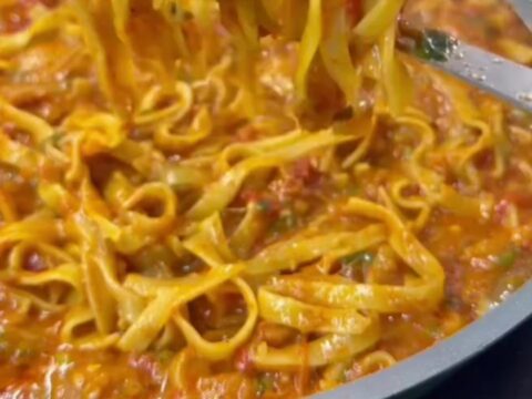 Skillet with cheesy tagliatelle and melted mozzarella, topped with parsley