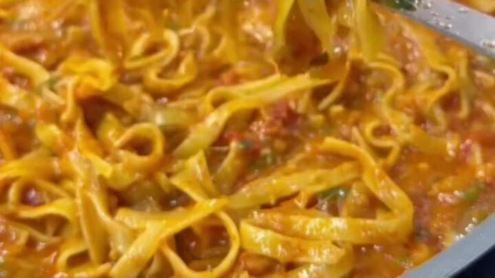 Skillet with cheesy tagliatelle and melted mozzarella, topped with parsley