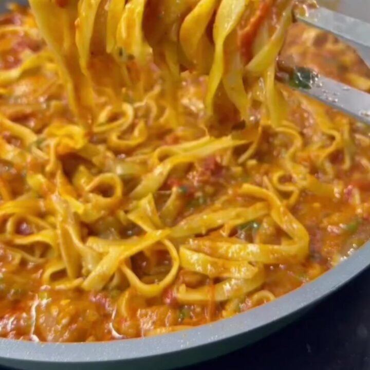 Skillet with cheesy tagliatelle and melted mozzarella, topped with parsley
