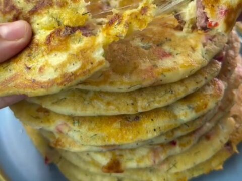 Giant stuffed pancake sliced into wedges, revealing melted cheese and sucuk pieces.