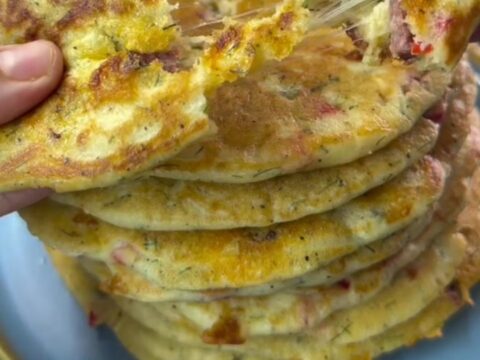 Savory pancake pizza wedges with melted cheese and sausage on a wooden board