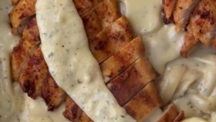 Creamy lemon garlic parmesan chicken fettuccine garnished with parsley and lemon wheels