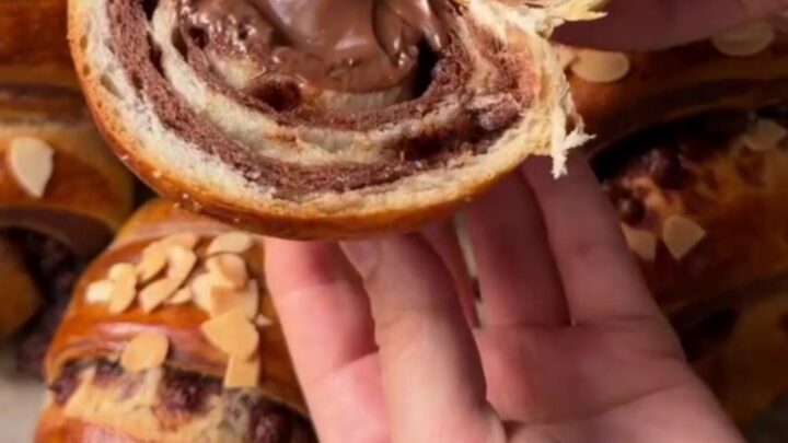 A warm zebra croissant poğaça pulled apart, showing molten chocolate and alternating dark and white swirls.