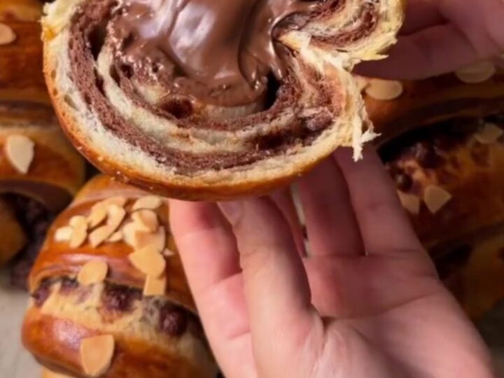 A warm zebra croissant poğaça pulled apart, showing molten chocolate and alternating dark and white swirls.