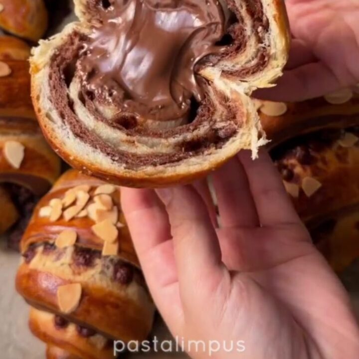 A warm zebra croissant poğaça pulled apart, showing molten chocolate and alternating dark and white swirls.