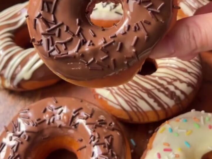 A stack of golden fried donuts dipped in milk chocolate and drizzled with white chocolate
