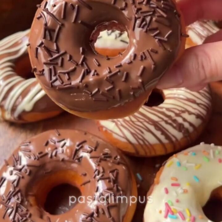 A stack of golden fried donuts dipped in milk chocolate and drizzled with white chocolate