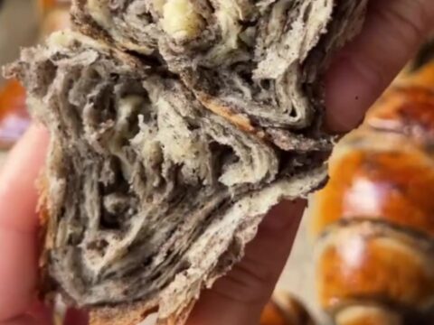 Golden spiral çörek buns with dark poppy seed filling, pulled apart to show flaky layers