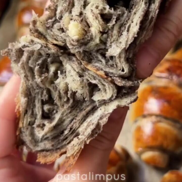 Golden spiral çörek buns with dark poppy seed filling, pulled apart to show flaky layers