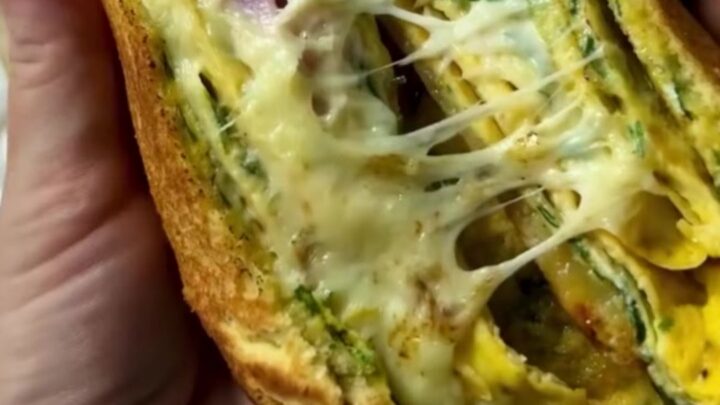 Crispy egg-dipped ham and cheese toastie sliced in half showing melted cheese pull