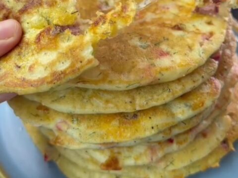Stack of savory pancakes with feta and dill on a plate