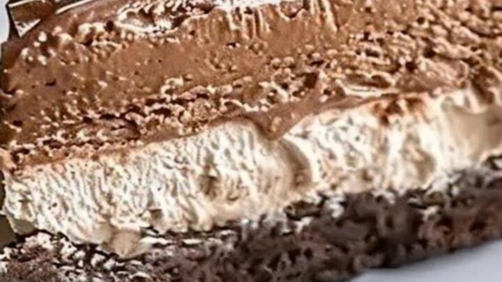A slice of triple chocolate mousse cake with piped rosettes on a white plate.