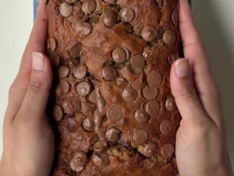 Sliced chocolate banana bread with melty chocolate pools on a wooden board