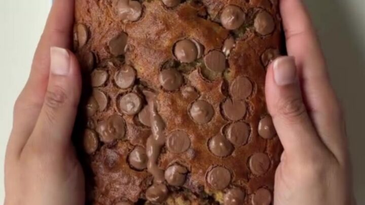 Sliced chocolate banana bread with melty chocolate pools on a wooden board