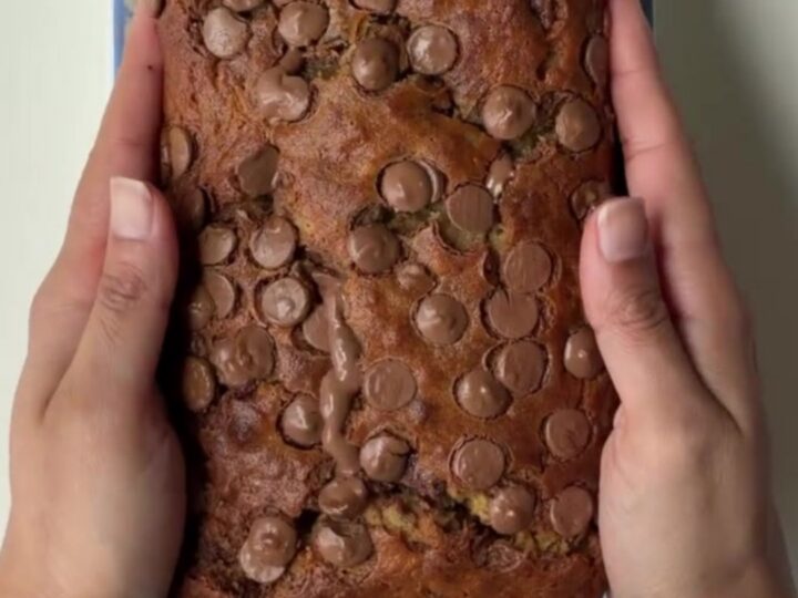 Sliced chocolate banana bread with melty chocolate pools on a wooden board