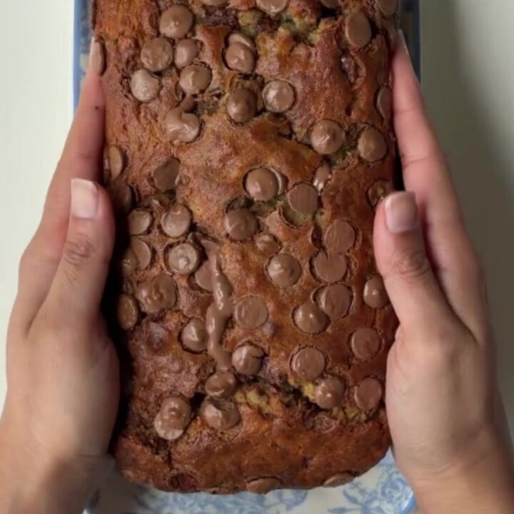 Sliced chocolate banana bread with melty chocolate pools on a wooden board