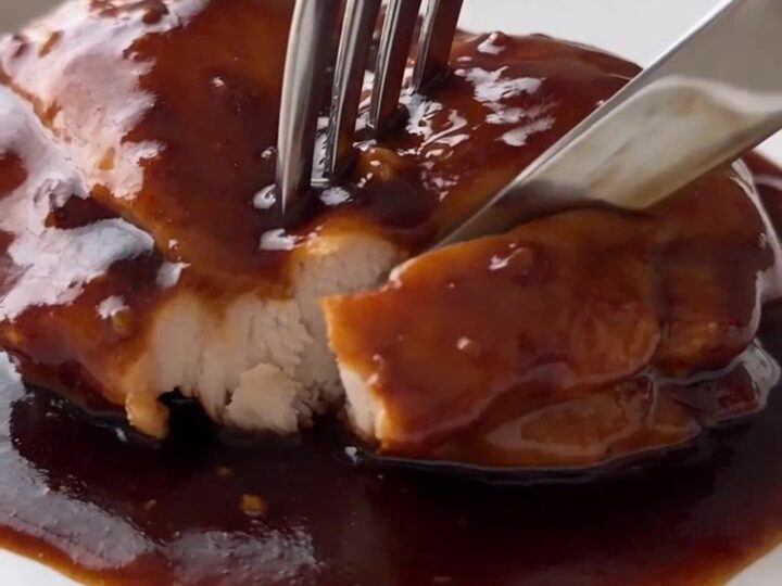 Slow cooker honey garlic chicken with glossy sauce in the crockpot, steam rising