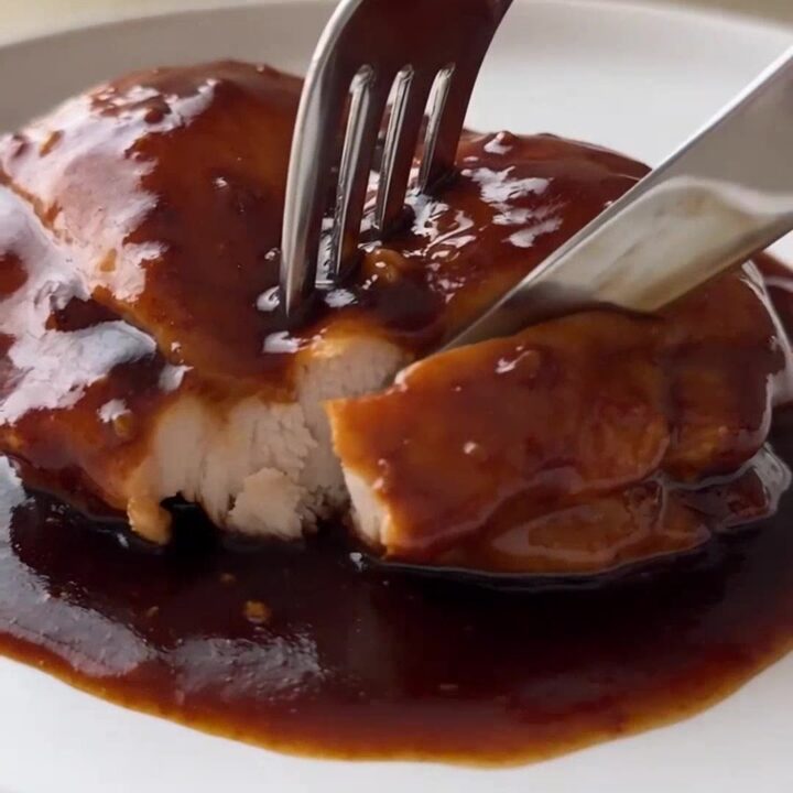 Slow cooker honey garlic chicken with glossy sauce in the crockpot, steam rising