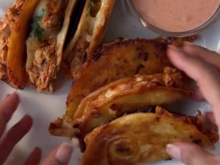 Cheesy chicken tacos on a baking sheet with melted cheese and toppings