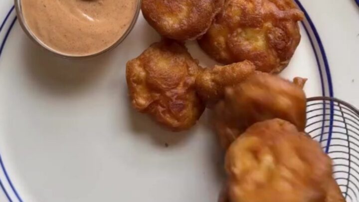 Crispy golden chicken nuggets piled in a basket with fries and Texas toast, with a cup of creamy pepper sauce for dipping.
