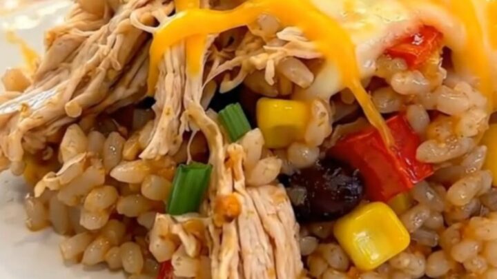 A serving of Southwest chicken casserole on a white plate, showing melted cheddar cheese, rice, beans, and corn.