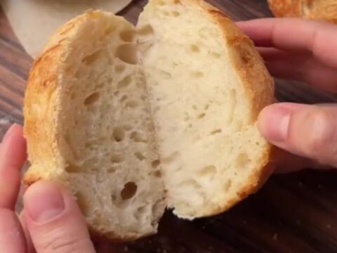 Crusty mini sourdough loaves with blistered golden crust on a wooden board