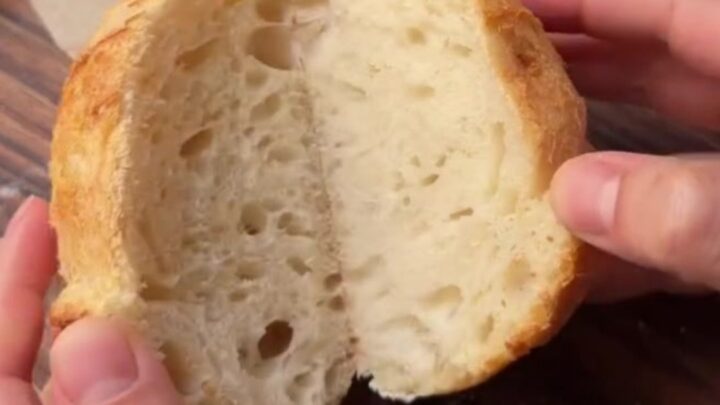 Crusty mini sourdough loaves with blistered golden crust on a wooden board