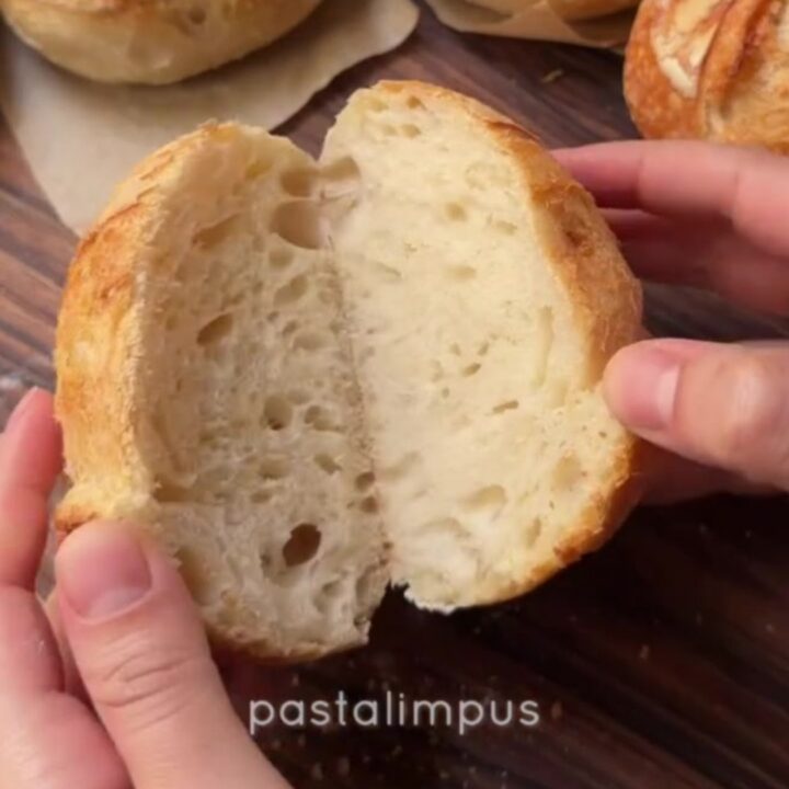 Crusty mini sourdough loaves with blistered golden crust on a wooden board