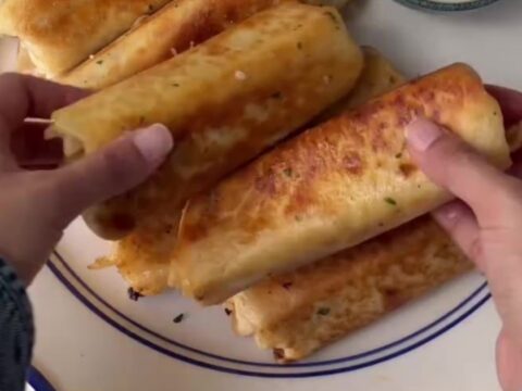 Crispy chicken Alfredo wrap sliced in half with melted mozzarella pulling
