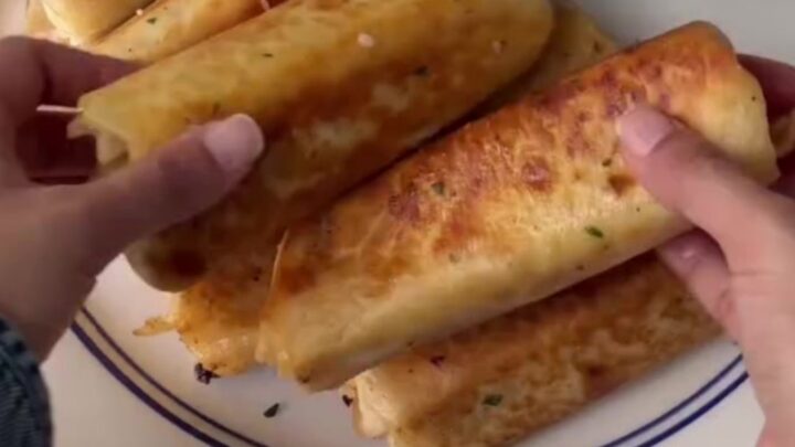 Crispy chicken Alfredo wrap sliced in half with melted mozzarella pulling