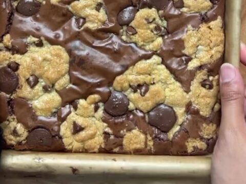 Thick brookie bar with a gooey chocolate chip cookie base and a dense brownie crown, sliced and broken in half