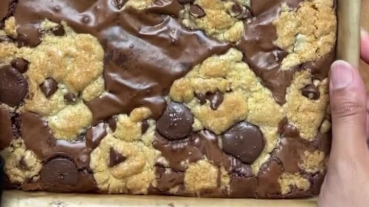 Thick brookie bar with a gooey chocolate chip cookie base and a dense brownie crown, sliced and broken in half