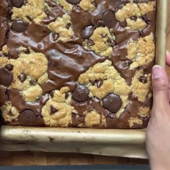 Thick brookie bar with a gooey chocolate chip cookie base and a dense brownie crown, sliced and broken in half