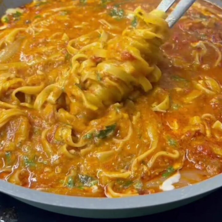Twirled tagliatelle pasta with glossy vegetable sauce, garnished with parsley and Parmesan