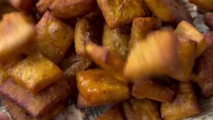 A pile of golden crispy potato snack chips on a paper towel, with one chip snapped in half showing airy interior.
