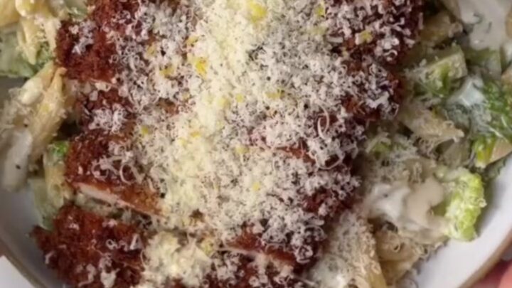Crispy chicken Caesar pasta salad in a bowl, topped with golden chicken strips and shaved Parmesan