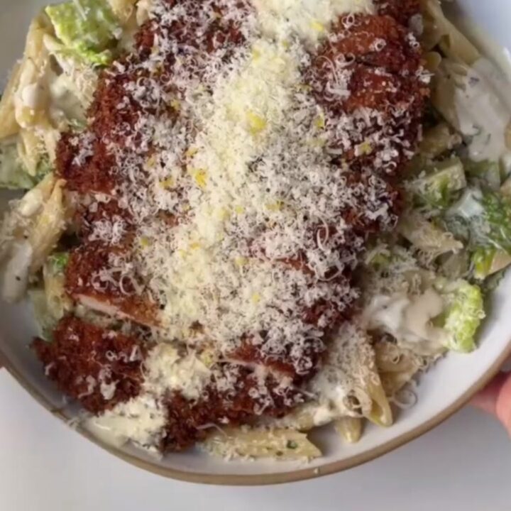 Crispy chicken Caesar pasta salad in a bowl, topped with golden chicken strips and shaved Parmesan