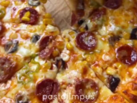 Bakery-style homemade pizza with stretchy cheese pull on a parchment-lined baking sheet