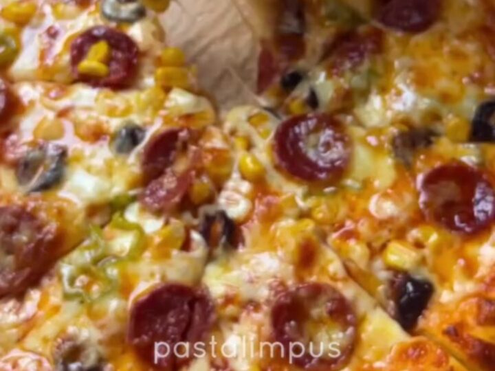 Bakery-style homemade pizza with stretchy cheese pull on a parchment-lined baking sheet
