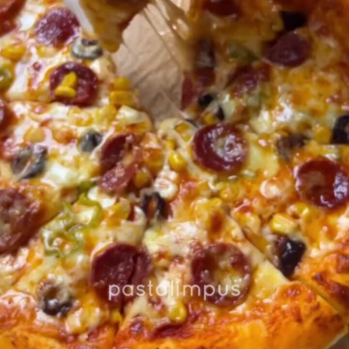Bakery-style homemade pizza with stretchy cheese pull on a parchment-lined baking sheet